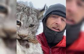 BC Farmer Chris Paulson holding Tuffnut the lynx by the back of the neck;