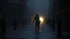 Two people walking in the dark towards a car light;